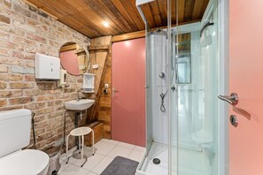 Een badkamer met een wit toilet, een wastafel, een spiegel en een douche met glazen wanden.