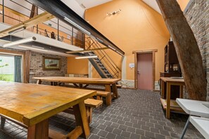 Een rustiek interieur met een trap, houten tafels en een bakstenen muur.