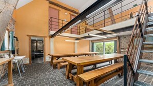Ein mehrstufiger Essbereich mit Holztischen und -bänken, einem Backsteinboden und einer Treppe.