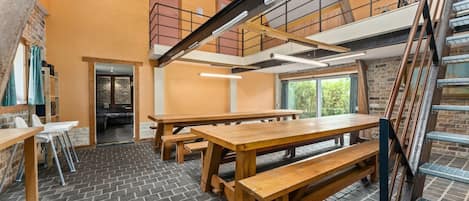 Un espace de restauration à plusieurs niveaux, avec des tables et des bancs en bois, un sol en briques et un escalier.