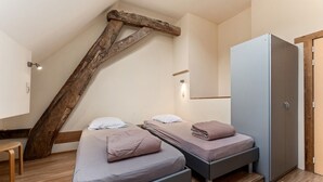 Ein Schlafzimmer mit zwei Betten, einem Kleiderschrank und einer Holzbalkenkonstruktion.