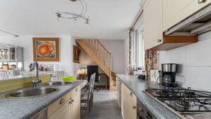 A modern kitchen with granite countertops, a gas stove, and a wooden staircase leading to another level.