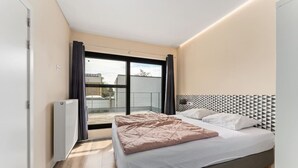 Un dormitorio moderno con una cama grande, un radiador y vistas al exterior.