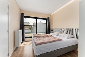 A modern bedroom with a large bed, a radiator, and a view of the outside. - Barbara`s Guesthouse (Poperinge)