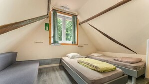 Una camera da letto soffitta accogliente con due letti, una finestra e una panca integrata.