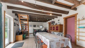 Zona pranzo con un tavolo lungo, sedie, una scala e un mobiletto in legno.