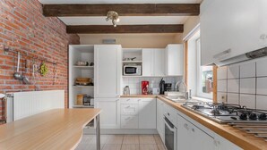 Una cucina con mobili bianchi, un piano cottura a gas, un forno a microonde e una parete in mattoni.
