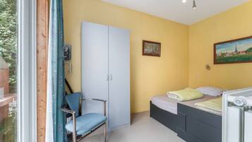 Una camera da letto con un letto, una sedia, un armadio e un quadro appeso al muro.