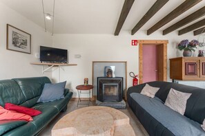 A living room with a fireplace, a television, a sofa, and a small table.