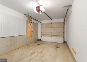 Een garage met een prikbord, een houten deur en een plafondlamp.
