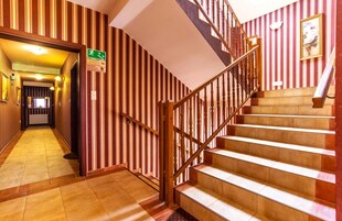 Un pasillo de hotel con una escalera de madera y empapelado a rayas.