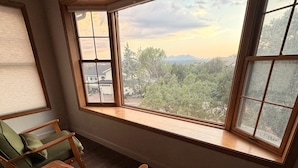 A room with a large window, a green sofa, and a wooden table. - The Pine Loft, Spacious Mountain Escape in Payson (Payson)