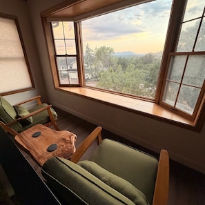 Quarto com uma janela grande, um sofá verde e uma mesa de madeira.