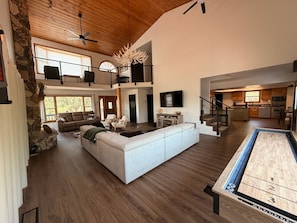 A spacious living area with a large sectional sofa, a fireplace, and a view of the kitchen.