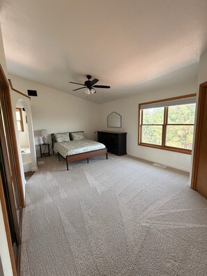 A bedroom with a bed, a ceiling fan, a dresser, a window, and a door. - The Pine Loft, Spacious Mountain Escape in Payson (Payson)