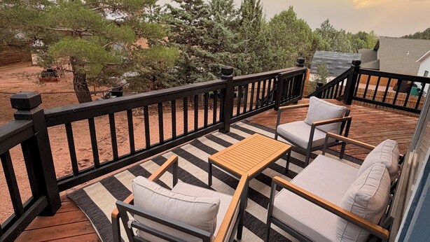 A wooden deck with outdoor furniture, a railing, and a view of trees and a distant building. - The Pine Loft, Spacious Mountain Escape in Payson (Payson)