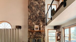 A spacious living room with a stone fireplace, a leather sofa, and a cowhide rug. - The Pine Loft, Spacious Mountain Escape in Payson (Payson)