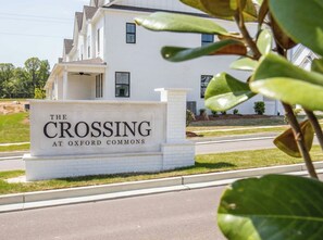 A white building with a sign that reads 'The Crossing at Oxford Commons.' - Rebel'ado-Colorado Roots-Oxford Style! 3 King Ensuites -Sleeps 8 (Oxford)
