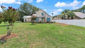 A two-story house with a front yard, a small tree, and a white fence. - Stillwater Cottage - Dock + Fishing (Brunswick)