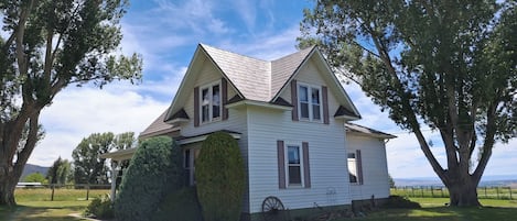 A single-story house with a gabled roof, surrounded by trees and a well-maintained lawn.