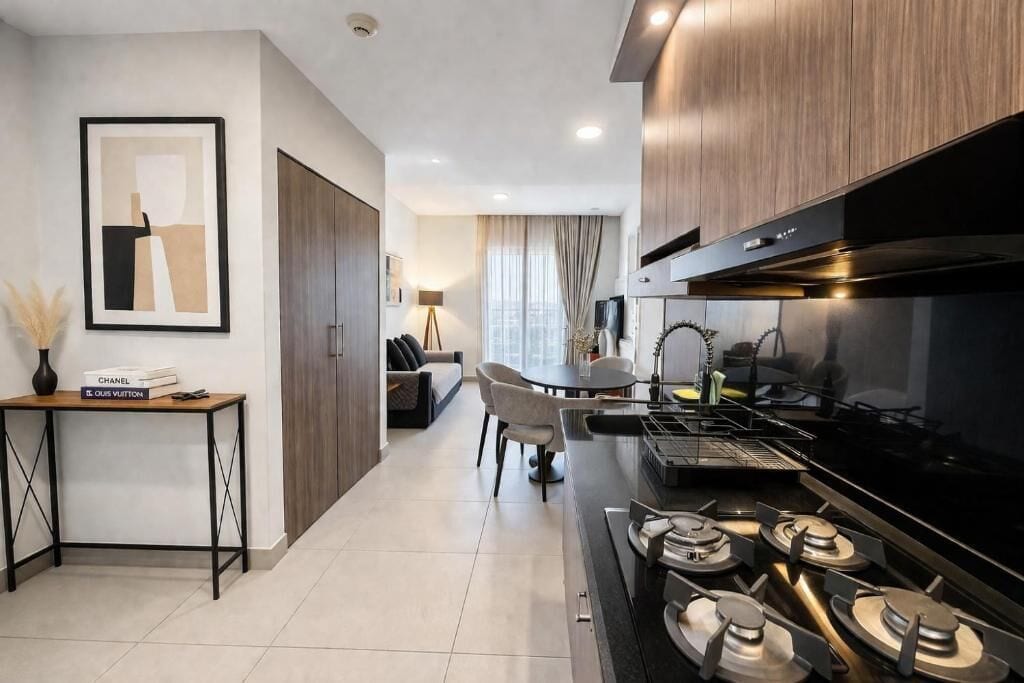 Une cuisine moderne équipée d’une cuisinière à gaz, un coin repas avec une table et des chaises, et un canapé à l’arrière-plan.