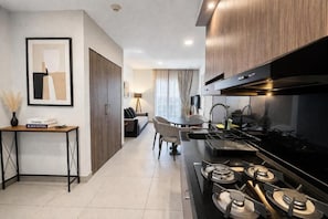 Una cocina moderna con estufa a gas, un comedor con mesa y sillas, y un sofá al fondo.