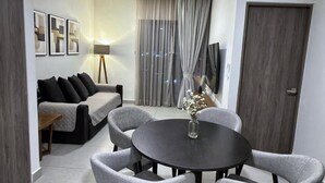 A modern living room with a sofa, a dining table with chairs, a TV, and a window with curtains. - Colonia10 by tuhost (Monterrey)