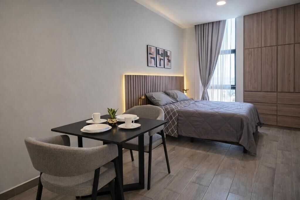 Una habitación de hotel moderna con una cama, una mesa de comedor con sillas y una pequeña mesa con una planta.