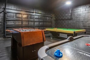 Ein Raum mit Kicker, Billardtisch und einem Kicker mit braunen Schränken.