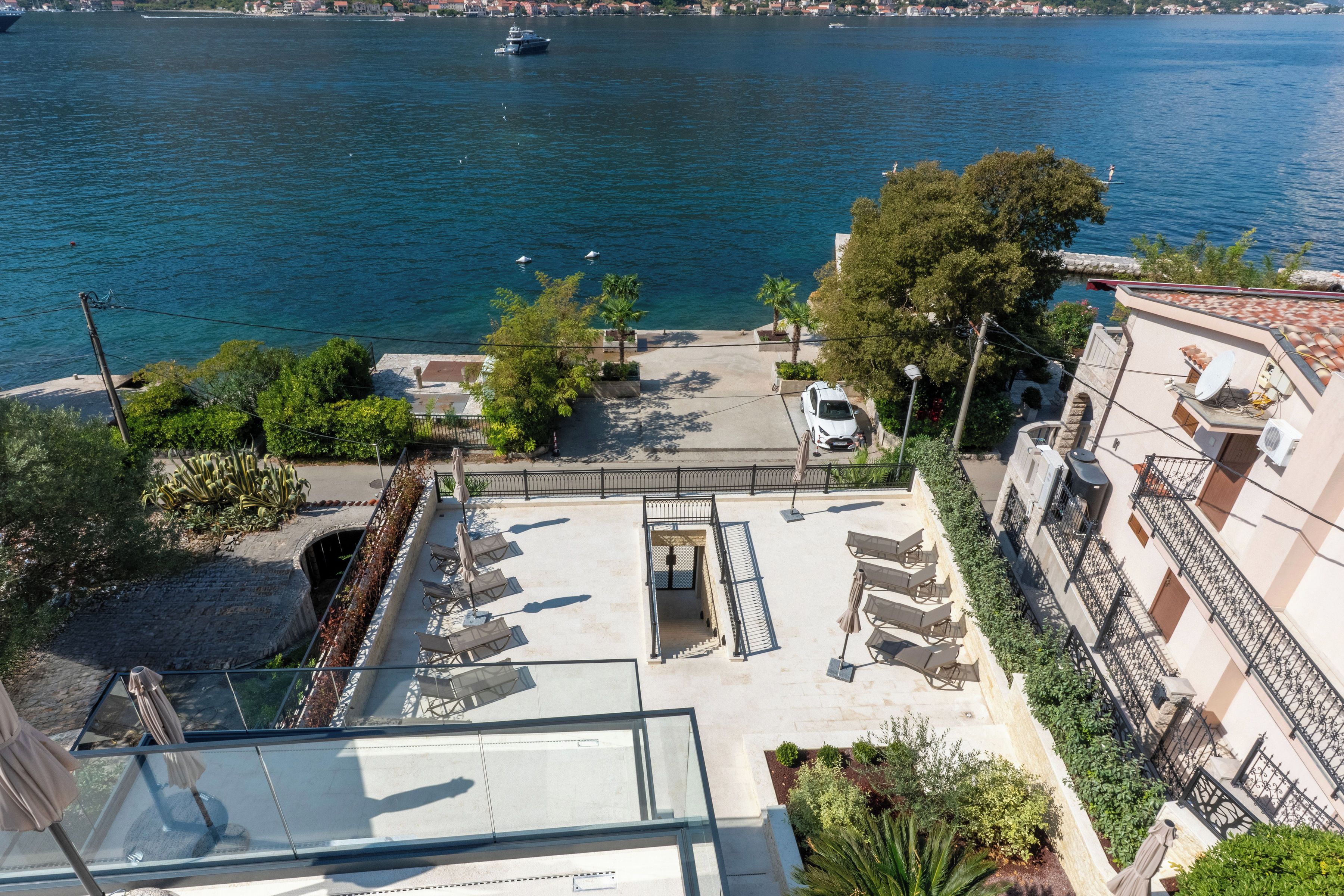 A coastal property with a view of the sea, a parking area, and a building with balconies.
