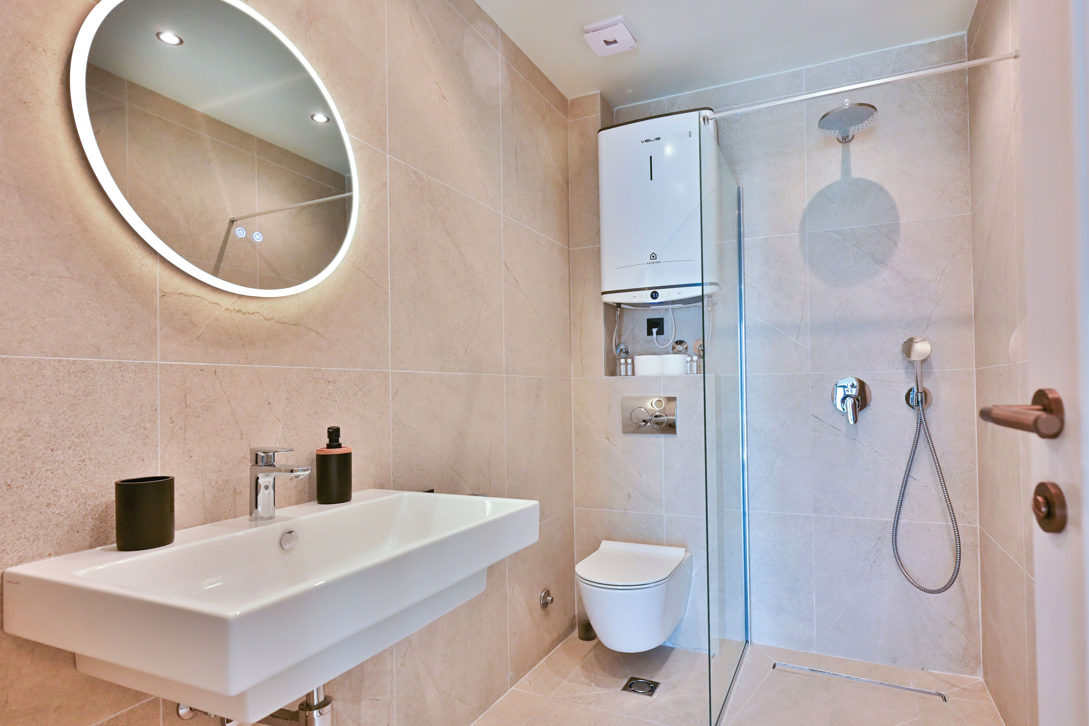 A modern bathroom with a large white sink, a toilet, and a glass-enclosed shower area.