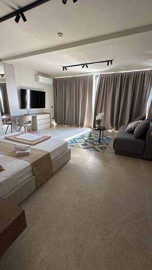 A modern living room with a sofa, a TV, a desk, and a dining area. - Ancora Adriatica (Kotor)