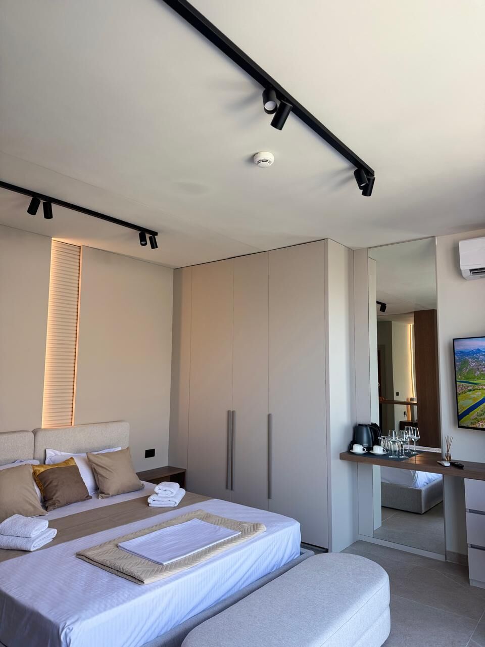 Een moderne hotelkamer met een bed, nachtkastje en een bureau met stoel.