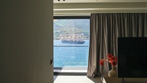 Una habitación con un ventanal grande, un televisor de pantalla plana y un florero con flores.