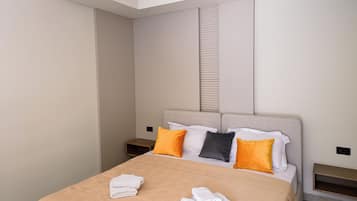 Une chambre d’hôtel avec un lit, des oreillers et une serviette pliée posée sur le lit.