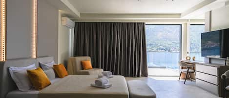 Una moderna camera d'albergo con un letto grande, una scrivania, una televisione e vista sull'acqua.
