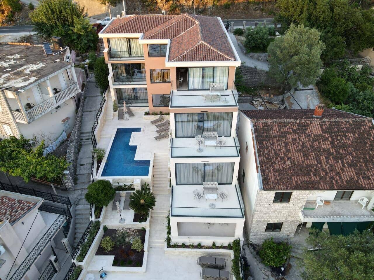 A multi-story residential building with a rooftop pool, balconies, and a garden area.