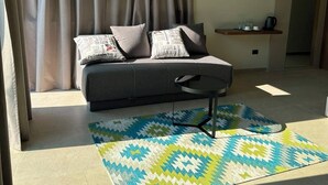 Una sala moderna con un sofá, una alfombra estampada y una cocina al fondo.