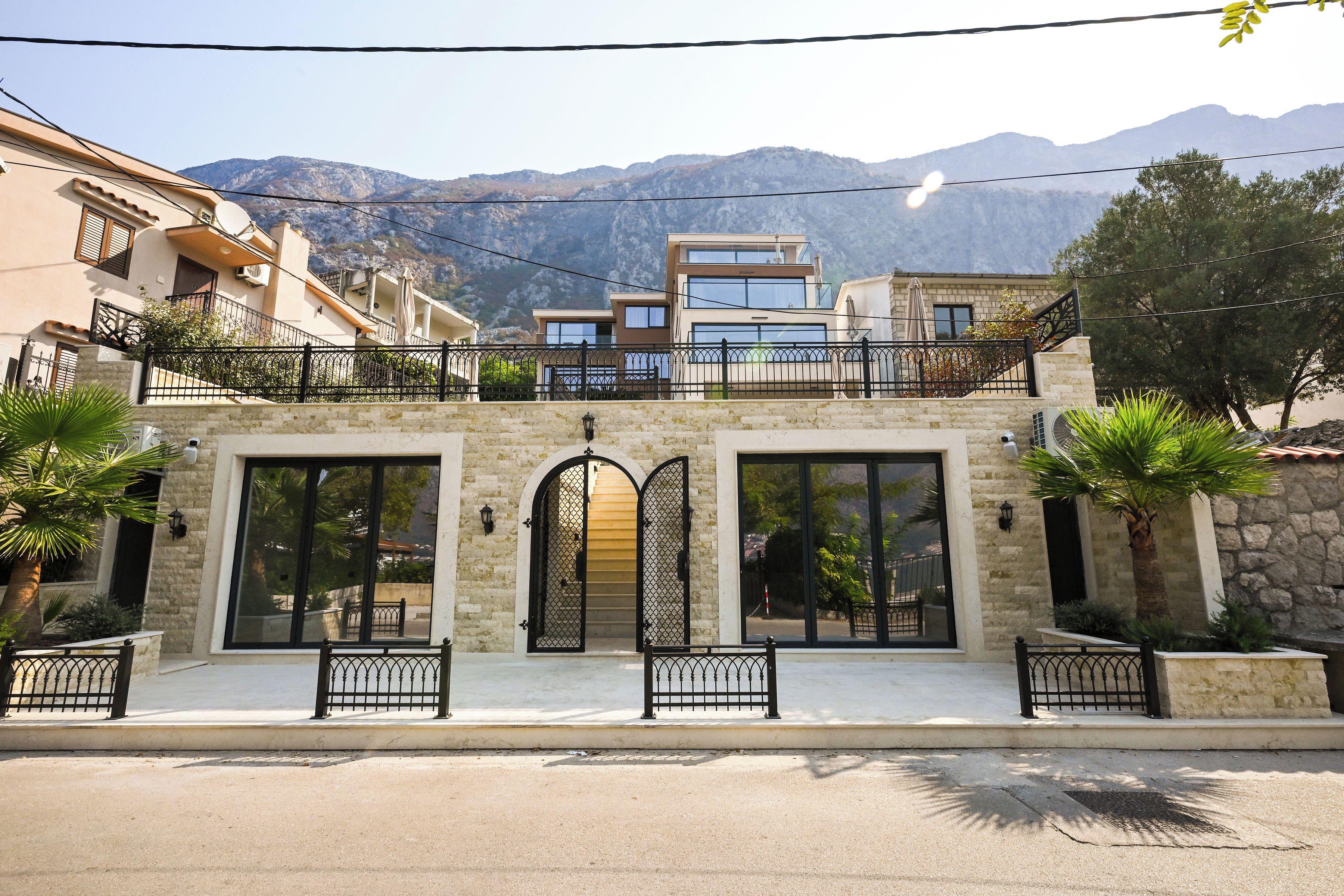 Un edificio de dos pisos con fachada de piedra, ventanas grandes y un balcón con barandilla de metal.