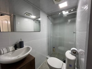 Ein Badezimmer mit weißem Waschbecken, Toilette und einer Duschkabine.