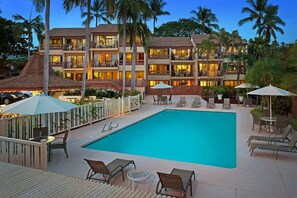 Ein Hotel mit Schwimmbad, Außenbereich zum Sitzen und mehreren Balkonen.