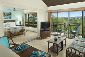 Ein Hotelzimmer mit Balkon, einem Bett, einem Fernseher und einer Sitzecke mit Blick auf die Landschaft.