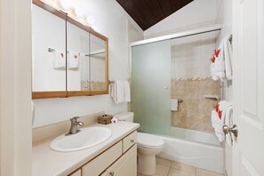 A bathroom with a double sink, a toilet, a bathtub, and a glass-enclosed shower.