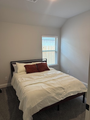 A bedroom with a bed, a window, and a wall socket.