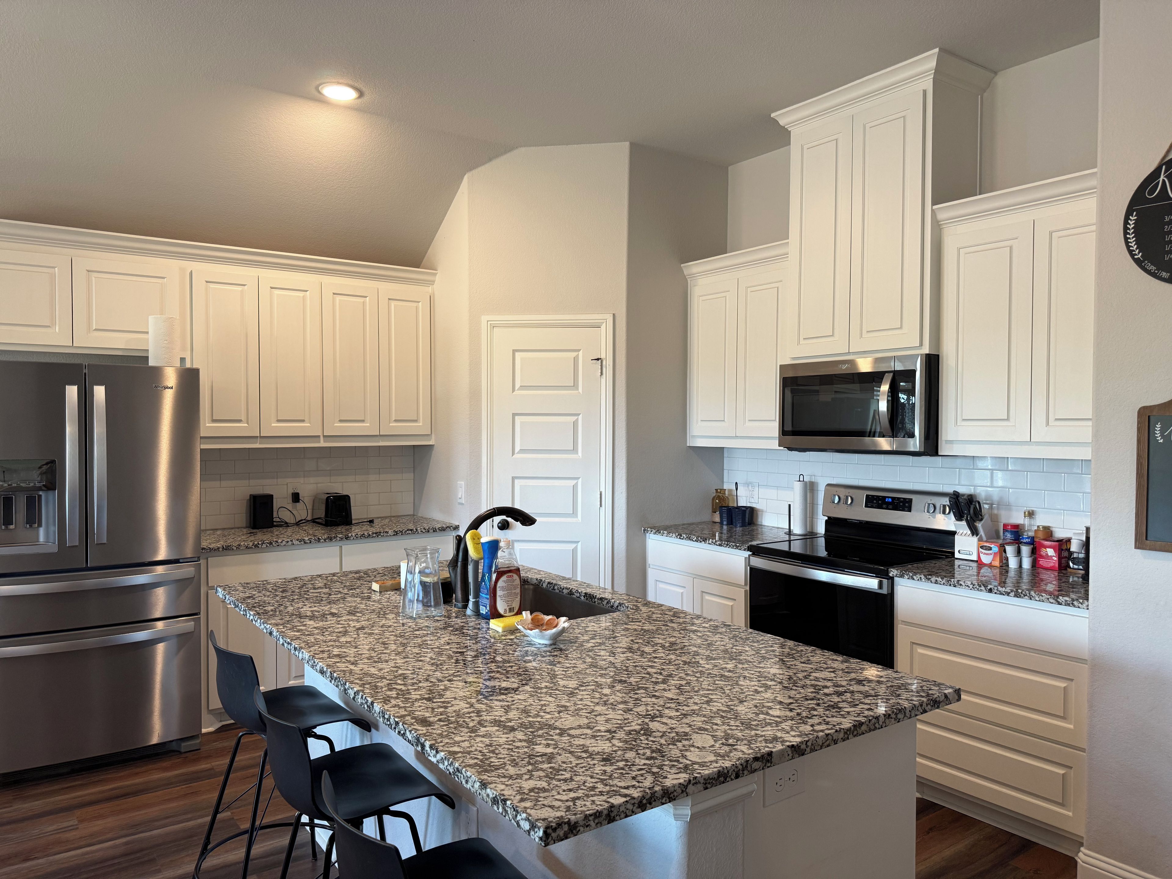 A modern kitchen with white cabinetry, stainless steel appliances, and a granite countertop.