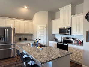 A modern kitchen with white cabinetry, stainless steel appliances, and a granite countertop.