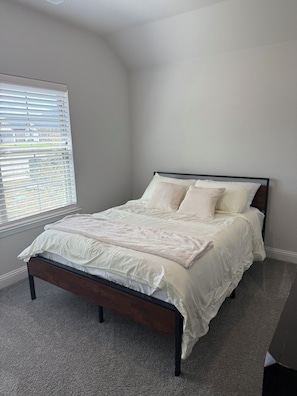 A bedroom with a bed, a window with blinds, and a carpeted floor. - Modern 3BR Home Near Hospital & Navarro College (Corsicana)
