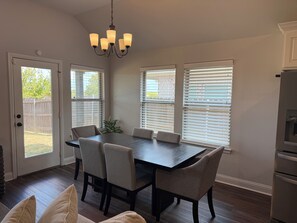 A dining area with a dark wooden table, beige upholstered chairs, and a chandelier. - Modern 3BR Home Near Hospital & Navarro College (Corsicana)
