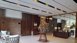 A modern lobby with a seating area, a decorative centerpiece, and a reception desk. - Cozy Retreat by Jane, UNIT 626 (Cebu City)