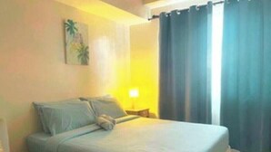 A hotel room with a bed, a nightstand, and a painting on the wall. - Cozy Retreat by Jane, UNIT 626 (Cebu City)